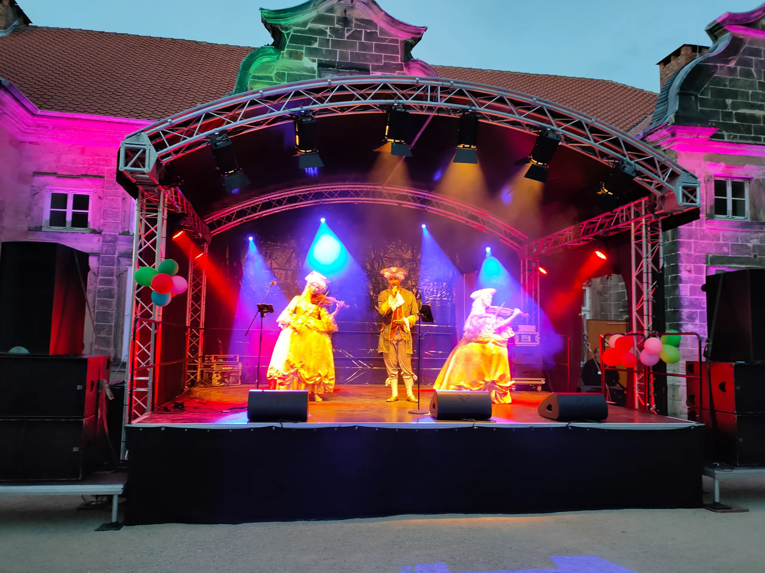 Person in historischer Kleidung spielt Geige auf Treppe.
