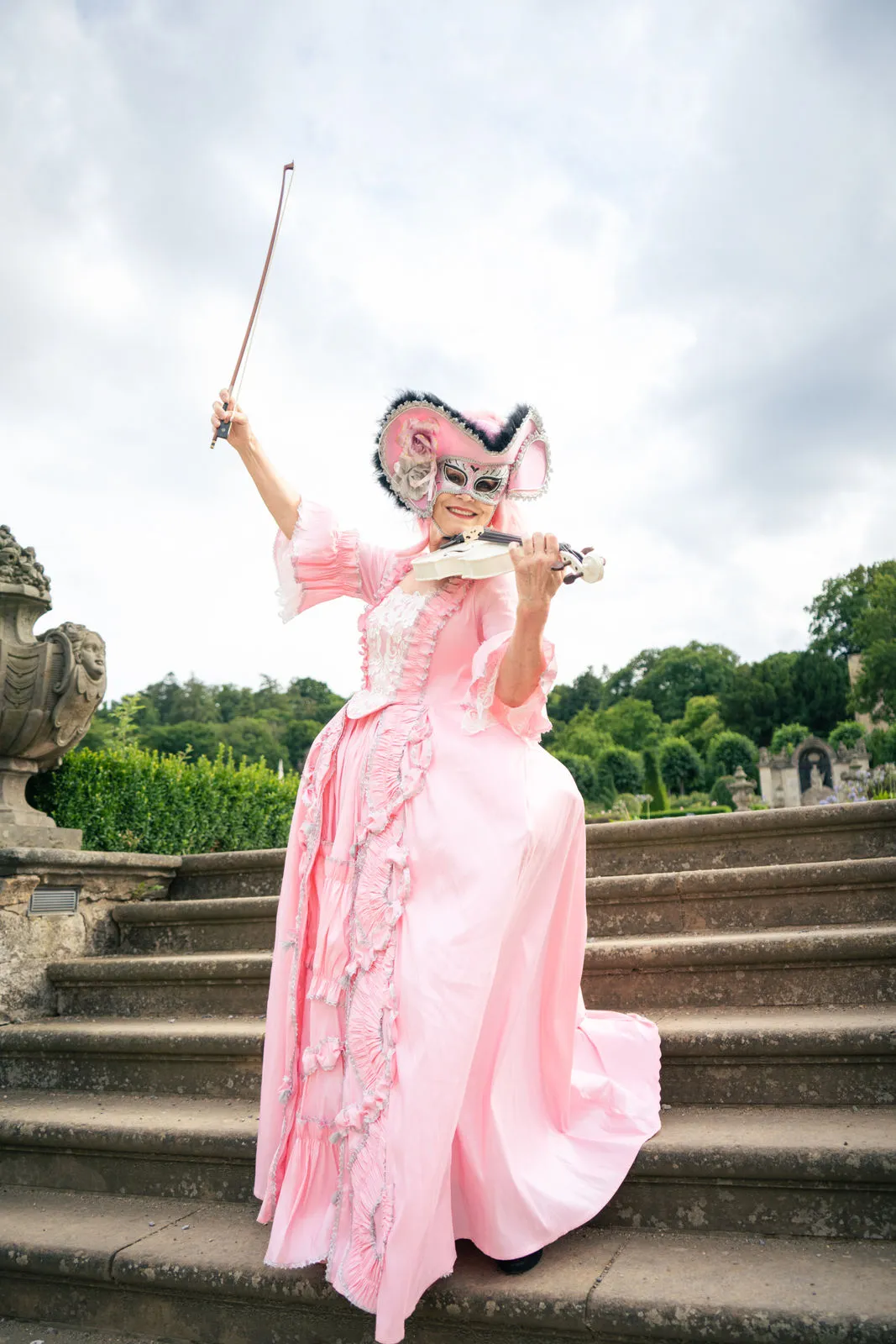 Person in historischer Kleidung spielt Geige auf Treppe.