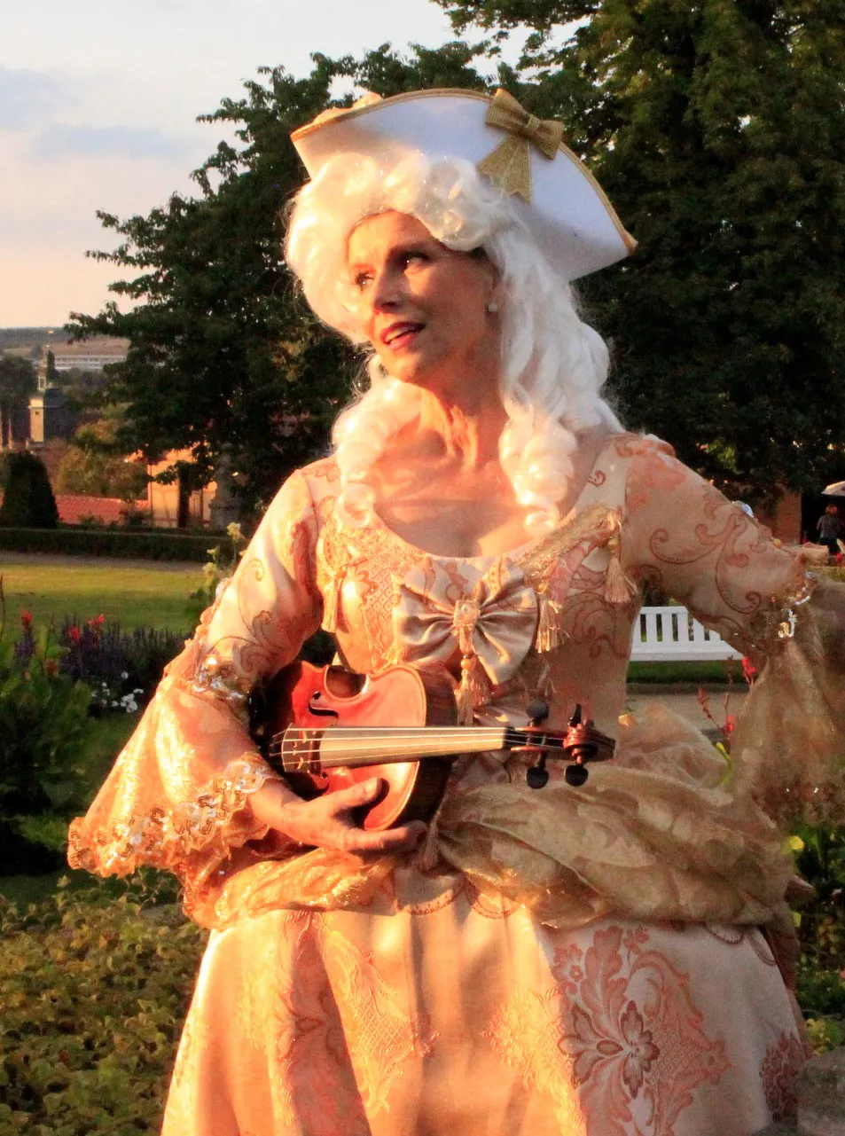 Person in historischer Kleidung spielt Geige auf Treppe.