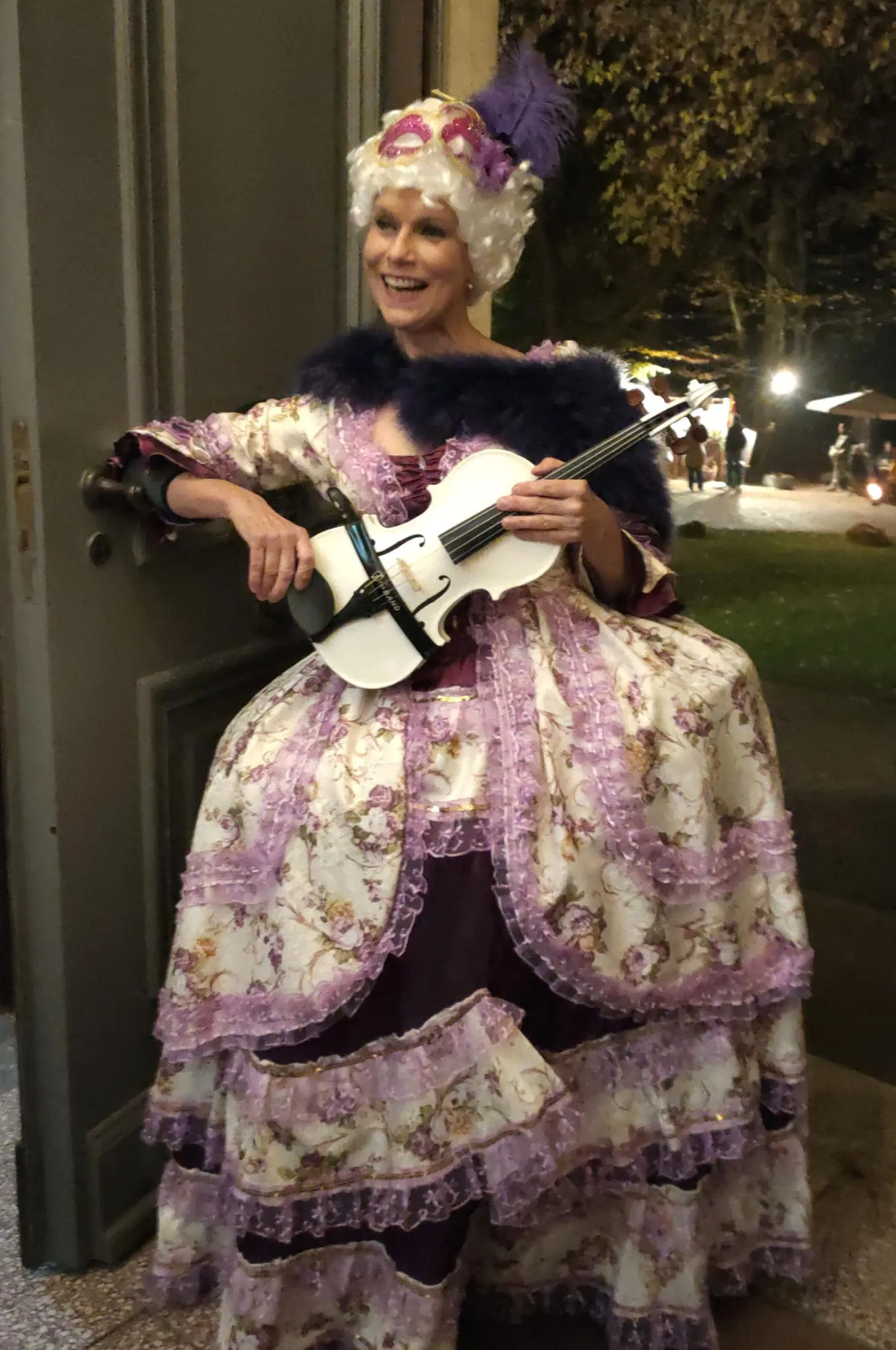Person in historischer Kleidung spielt Geige auf Treppe.