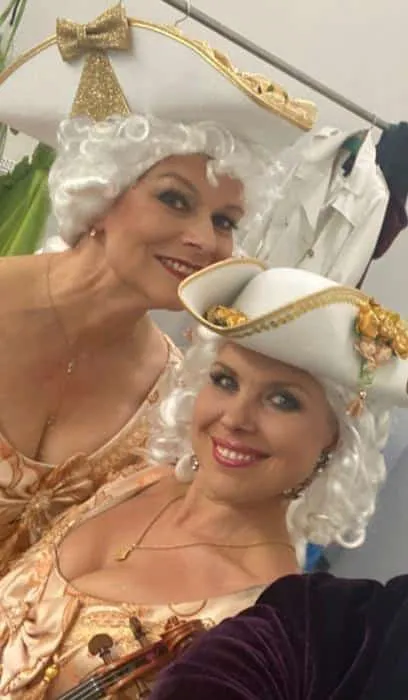 Person in historischer Kleidung spielt Geige auf Treppe.